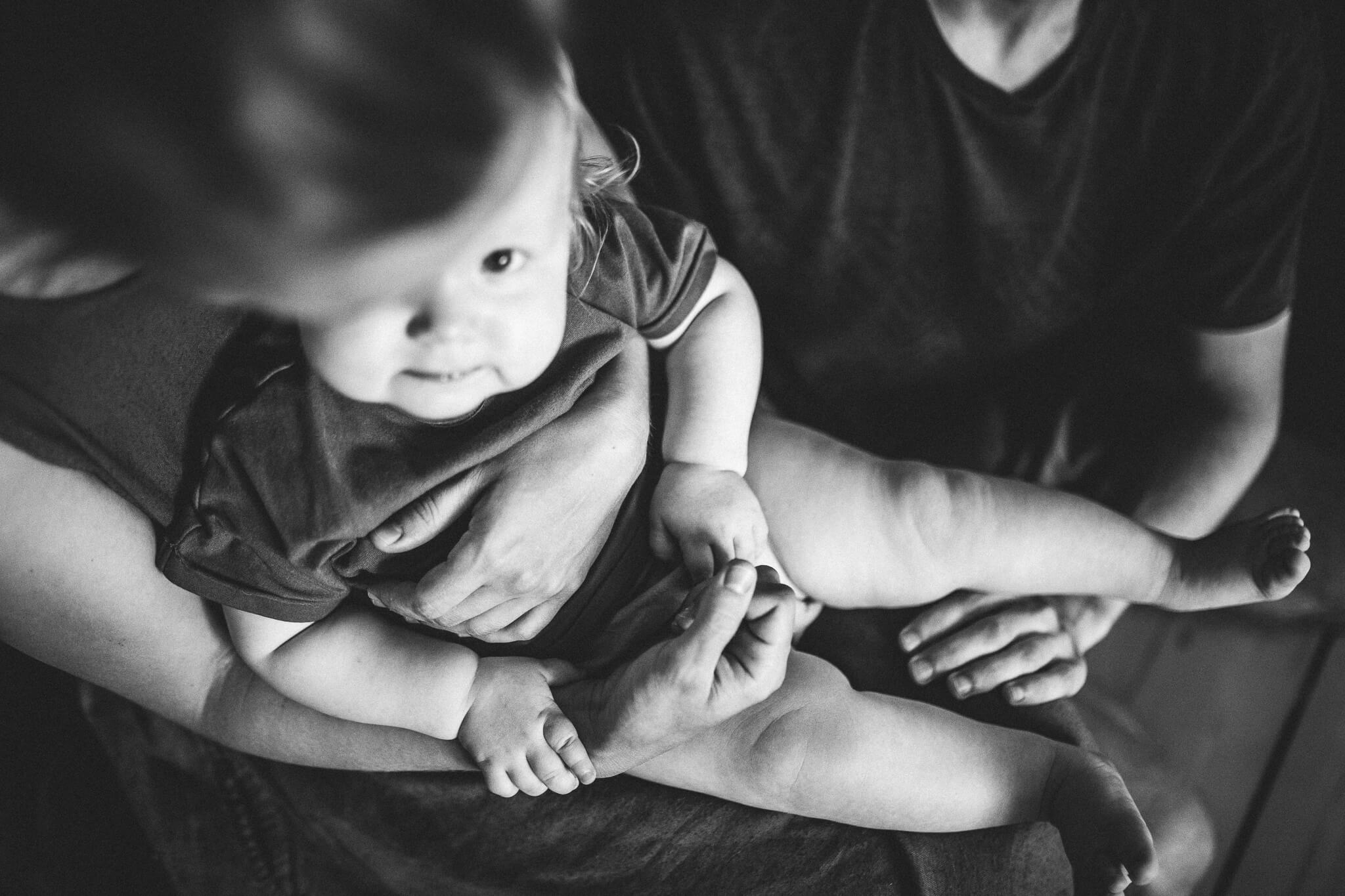 Mustvalge lähifoto lapse, ema ja isa kätest ja jalgadest.